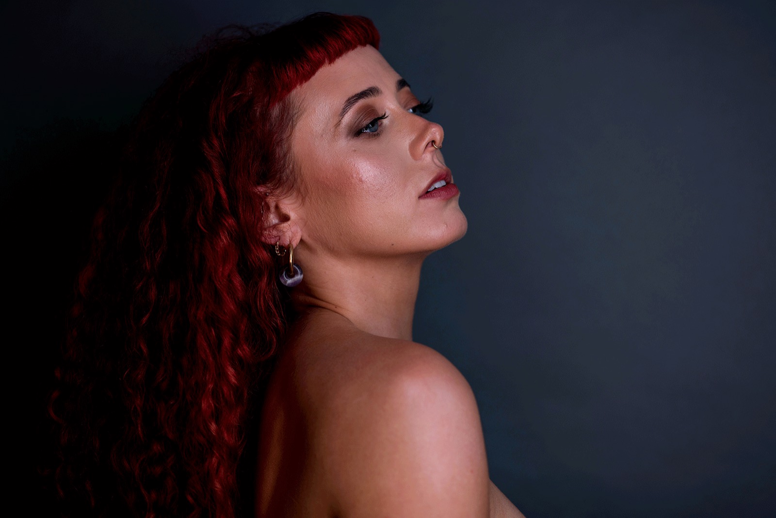 Emily Lamey in profile, chin lifted, against a dark background.