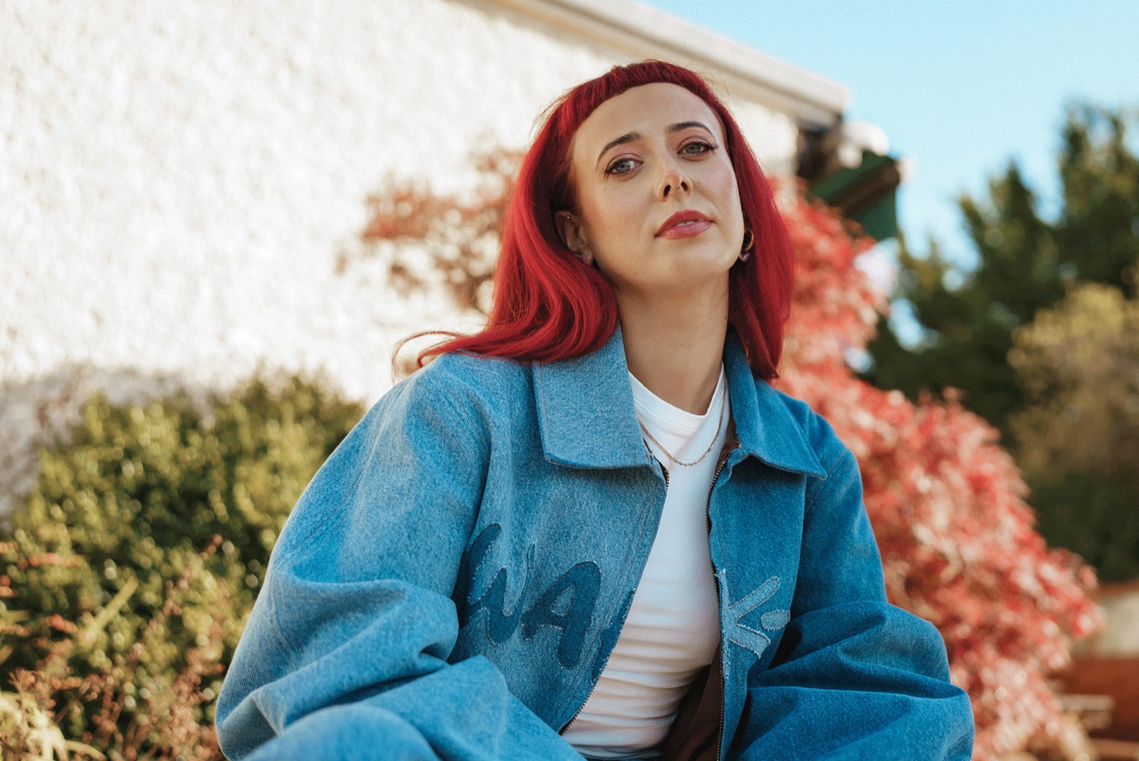 Emily Lamey in a denim jacket among autumn maple leaves.
