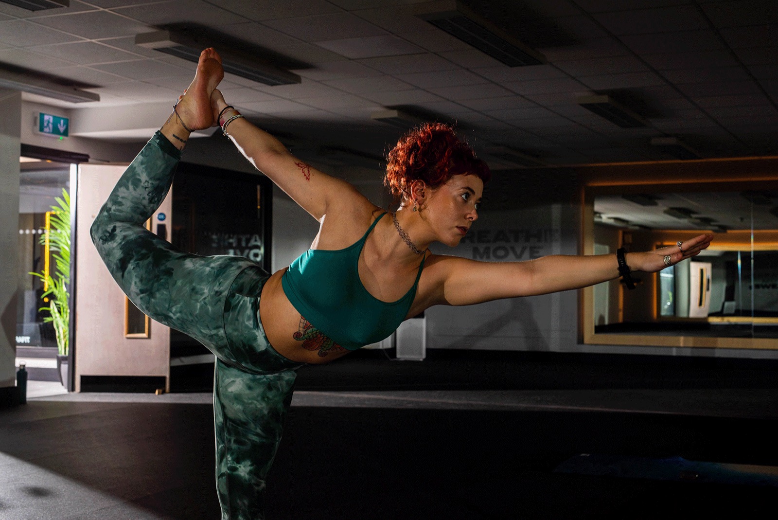 Emily Lamey holding standing bow pose in a studio.