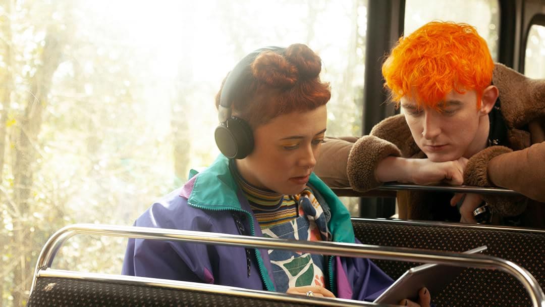 Emily Lamey wearing headphones on a bus beside a boy with orange hair in The Glenarma Tapes.